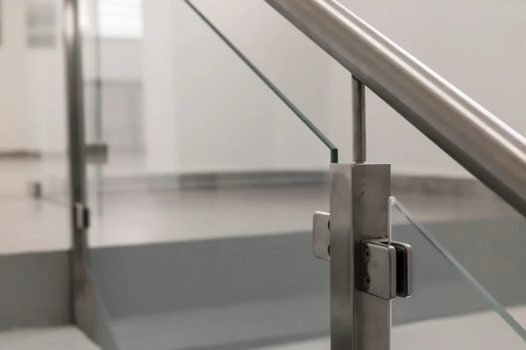 Close-up of a stainless post and clamps holding a glass railing panel